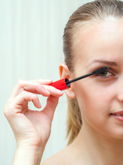 Woman applying mascara on eyelashes