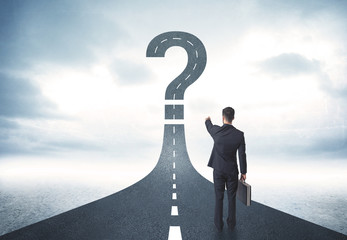 Business person lokking at road with question mark sign