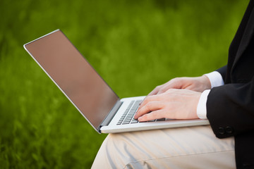 Businessman pressing modern laptop computer on colorful backgrou