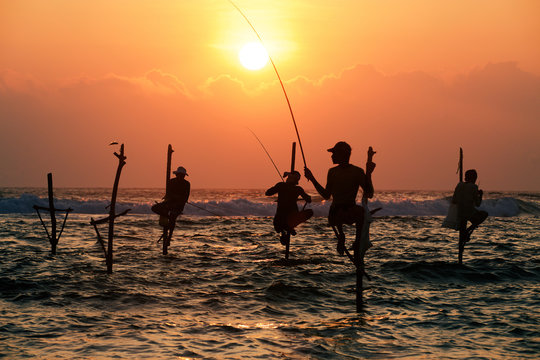 Silhouettes of the traditional fishermen at the sunset not far f