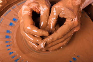 Fototapeta premium hands of artisan working with clay on pottery wheel