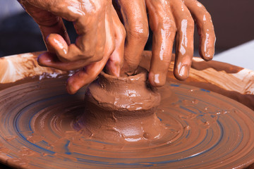 hands of potter shaping an edge on the jug