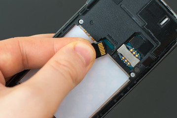 Male hand inserting Micro SD card to mobile phone.