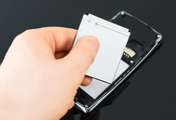Male hand inserting battery to mobile phone.