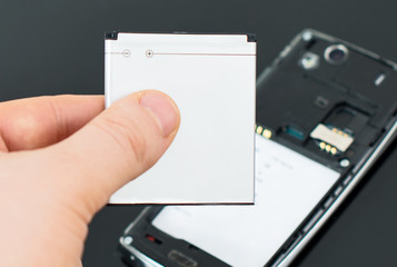 Male hand inserting battery to mobile phone.