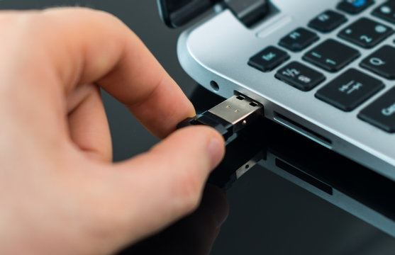 Hand plugging usb flash drive to laptop.