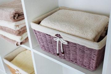 Fototapeta na wymiar Pile of towels with wicker basket on shelves of rack background