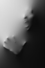 Screaming human face with hand pressing through fabric as horror background