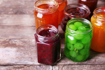 Homemade jars of fruits jam on rustic wooden background