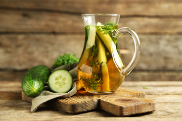 Glass ewer with fresh organic cucumber water on wooden table