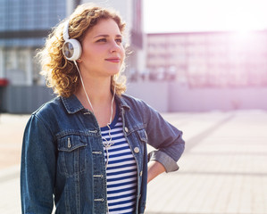 Hipster curly woman listening to music in the city