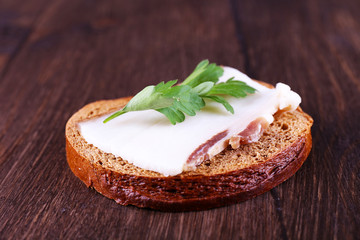 Sandwich with lard and parsley on wooden background