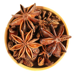 Star anise in wooden bowl, isolated on white