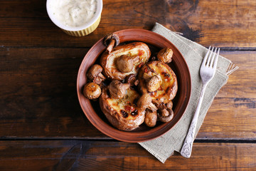 Baked potatoes with mushrooms in bowl and sauce