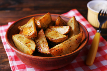 Baked potatoes in bowl and sauce on table close up