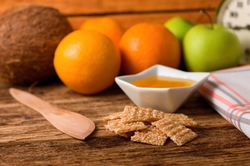 Broken sesame biscuits in front of honey and fruit