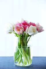 Beautiful tulips in glass vase on light background