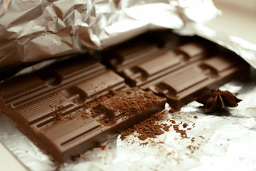 Bar of chocolate with cocoa and star anise on foil, closeup