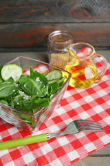Glass bowl of green salad with cucumber and spinach