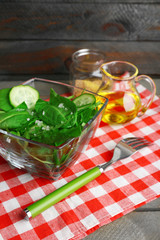 Glass bowl of green salad with cucumber and spinach