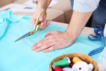 Obraz na płótnie Canvas Male dressmaker cut fabric on table