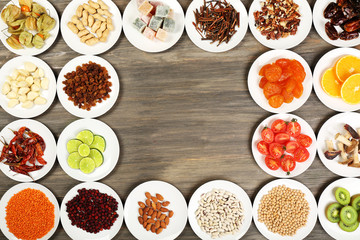 Different products on saucers on wooden table, top view
