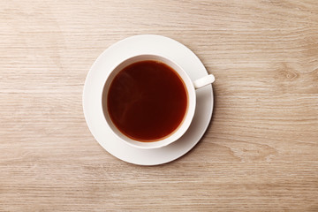 Cup of coffee on wooden table, top view