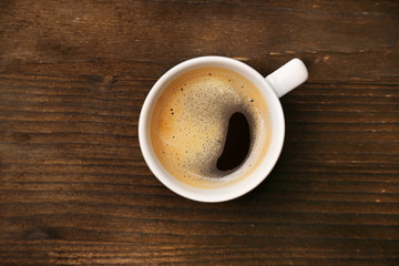 Cup of coffee on wooden table, top view