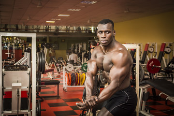Handsome black male bodybuilder posing in gym