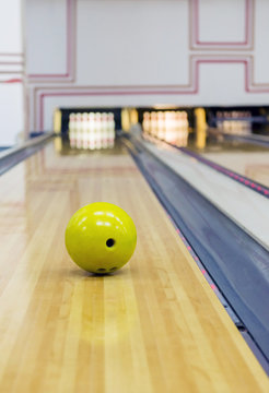 Yellow Bowling Ball Rolling Toward Pins