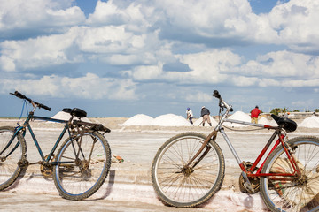 Obraz premium Viejas bicicletas oxidadas y hombres trabajando en las piscinas de evaporación en la mina de sal a cielo abierto de Manaure en la Guajira en Colombia
