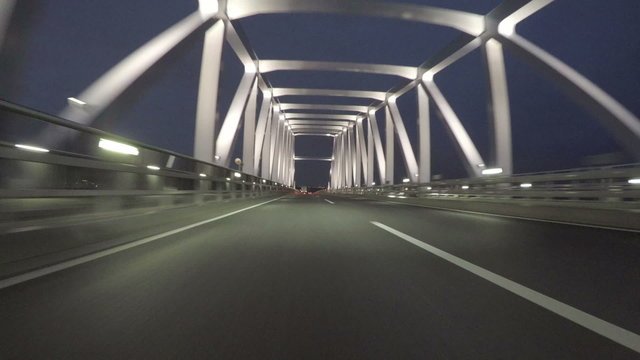 Driver's POV through the modern Tokyo Gate Bridge at twilight.