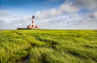 Fototapeta na wymiar Traditional lighthouse at North Sea with blue sky and clouds