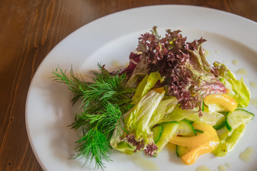 vegetable salad on a white plate, standing on a wooden base