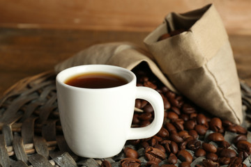 Cup of coffee with beans on rustic wooden background