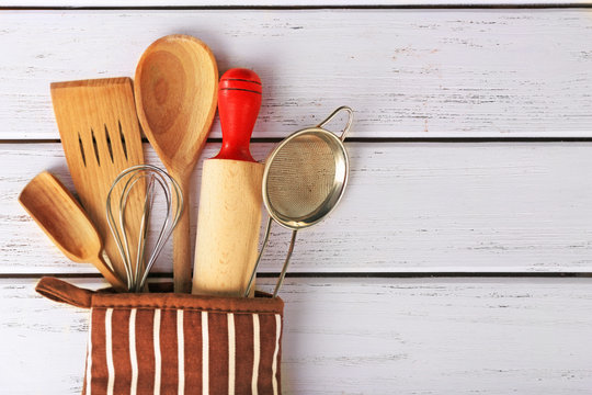 Set of kitchen utensils in mitten on wooden background