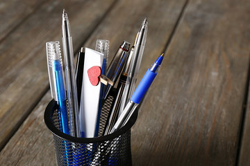Different pens in metal holder with paper notes