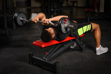 Young man doing arms bench french press workout in gym