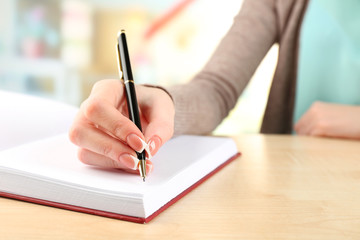 Female hand with pen writing on notebook, closeup
