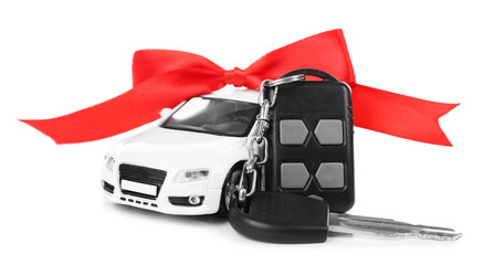 Keys with red bow near car as present isolated on white