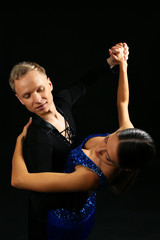 Beautiful couple of professional artists dancing on black background