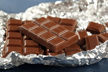Chocolate in foil on wooden table, closeup