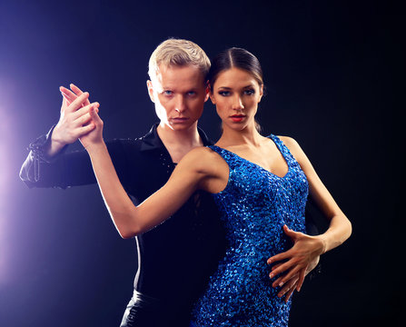Beautiful couple of professional artists dancing on black background