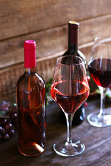 Bottles and glasses of wine with grape on wooden background