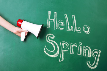 Hand holding megaphone on blackboard background