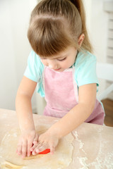 Obraz na płótnie Canvas Little girl preparing cookies in kitchen at home