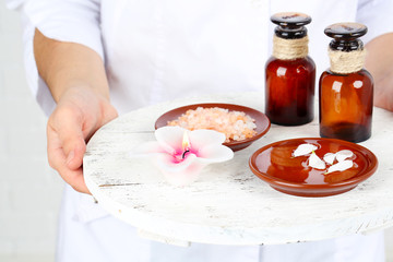 Beauty therapist holding tray of spa treatments, close-up