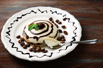 Tasty panna cotta dessert on plate, on wooden table
