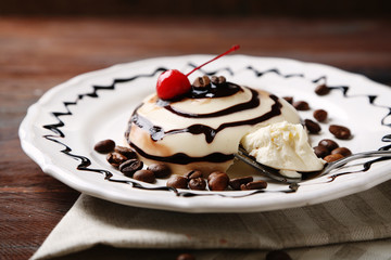Tasty panna cotta dessert on plate, on wooden table