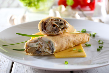 Pancakes with cream and mushrooms on wooden table, closeup